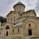 Vista frontal de la histórica Academia de Gelati bajo un cielo azul claro, reflejando su importancia como patrimonio cultural en Georgia.