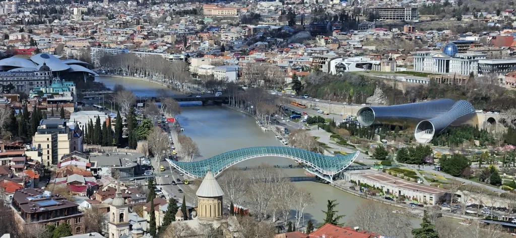 Vista panorámica del antiguo Tbilisi, con sus tejados coloridos y monumentos históricos, visto desde las antiguas murallas de la Fortaleza de Narikala, destacando la rica historia y belleza natural de Georgia, el país del Cáucaso.