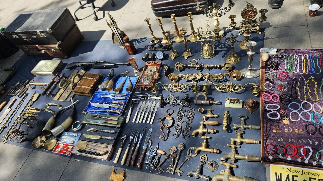 Variedad de antigüedades y objetos vintage en el mercadillo del Puente Seco de Tbilisi, incluyendo herramientas, candelabros, cubiertos y joyería